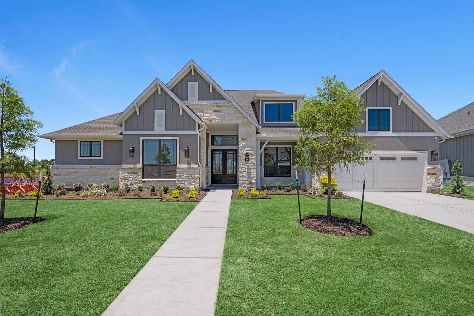New craftsman-style home with gray board-and-batten gables, stone accents and a freshly sodded front lawn
