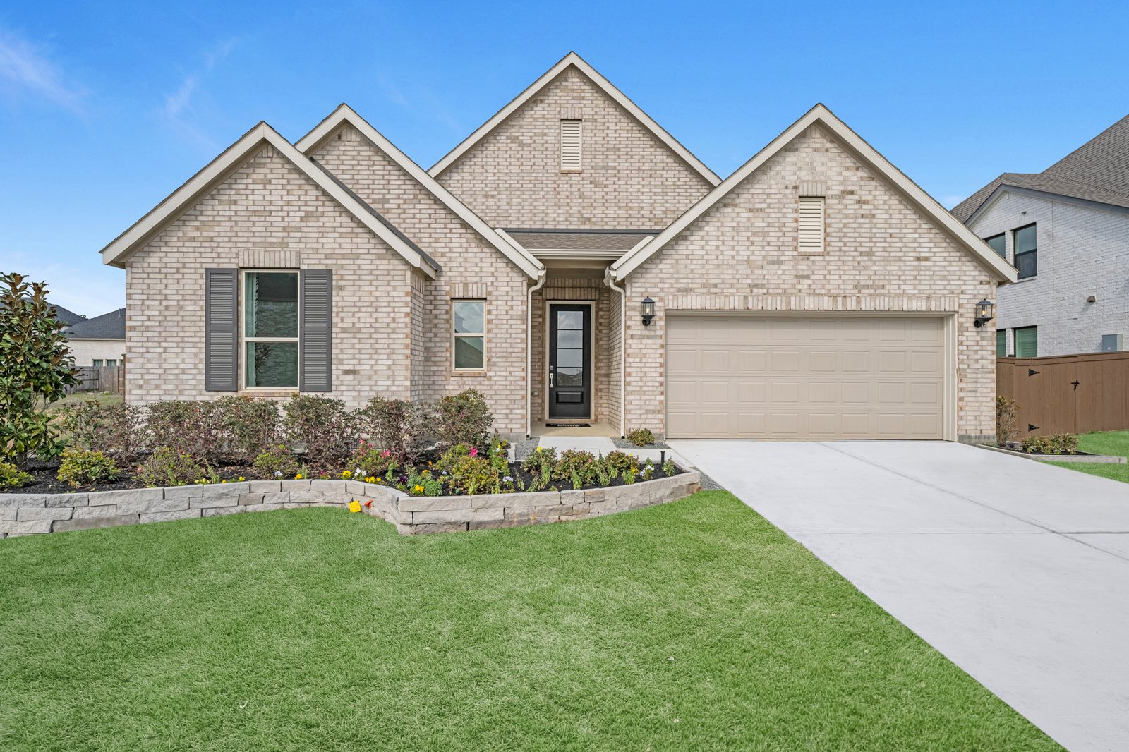 Single-story brick new build with triple gables, dark shutters and a front-entry two-car garage