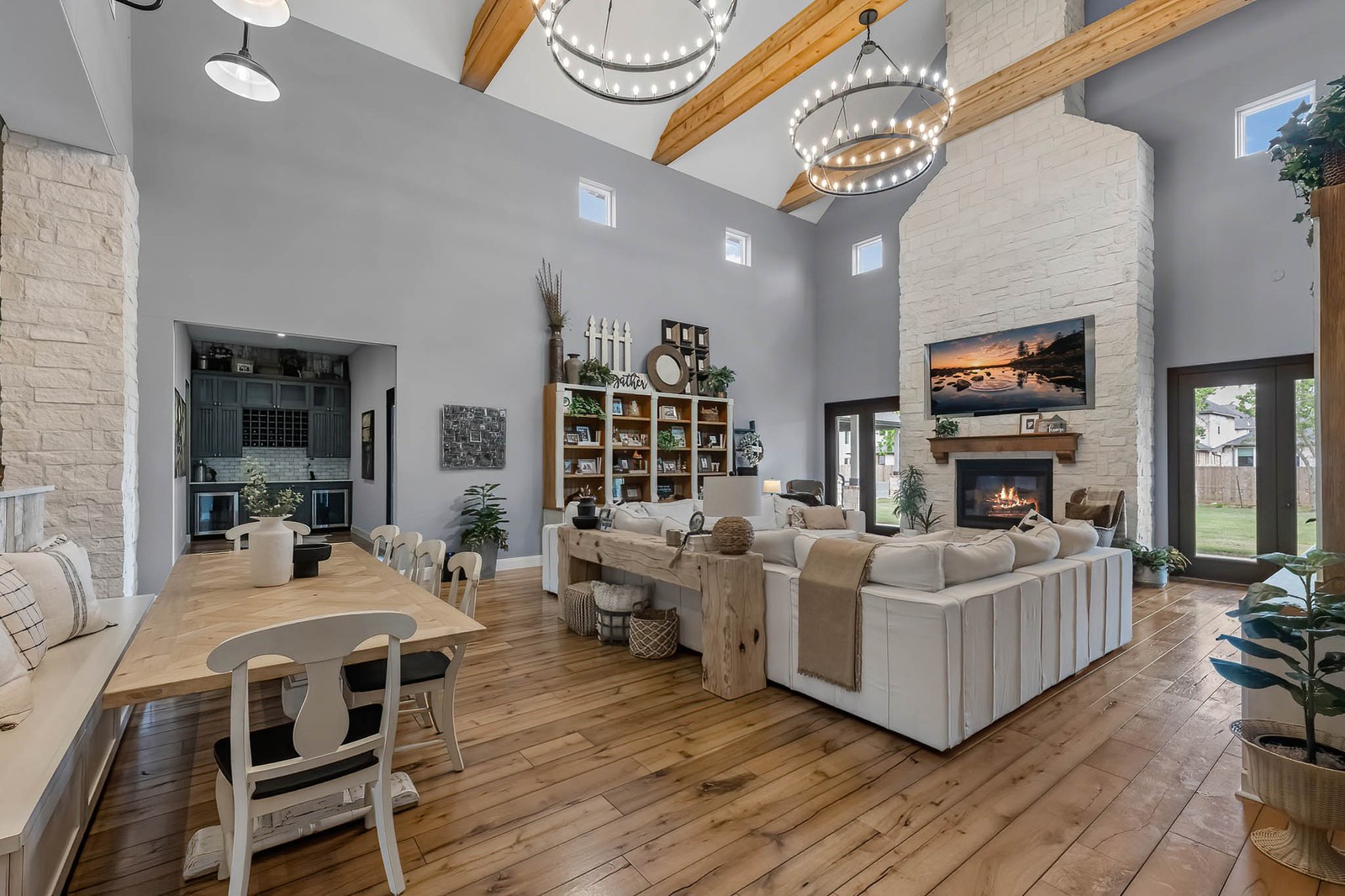 Open great room with a beamed vaulted ceiling, stone fireplace and dining table