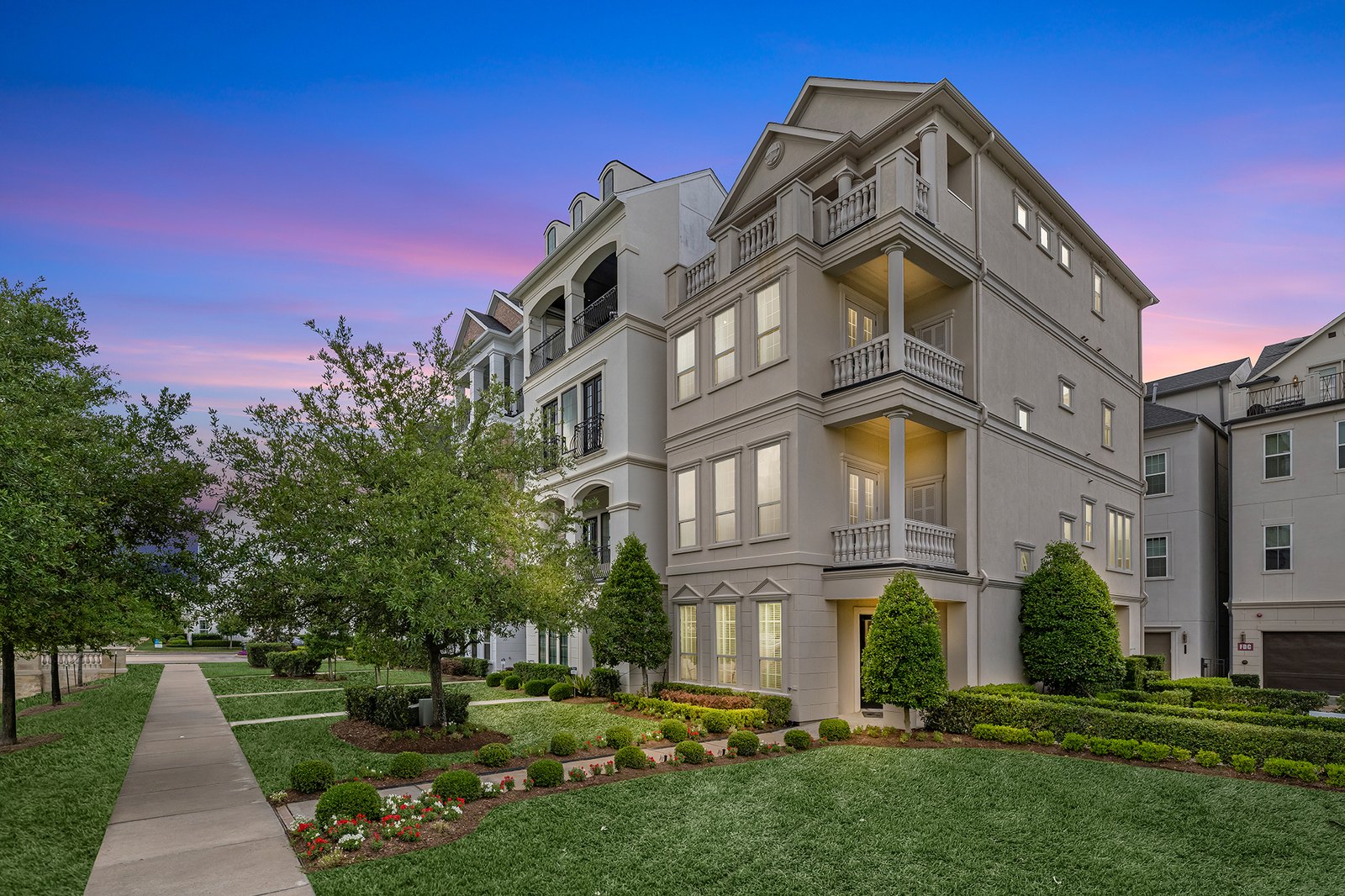 Virtual twilight of a four-story townhome under a pink and blue dusk sky