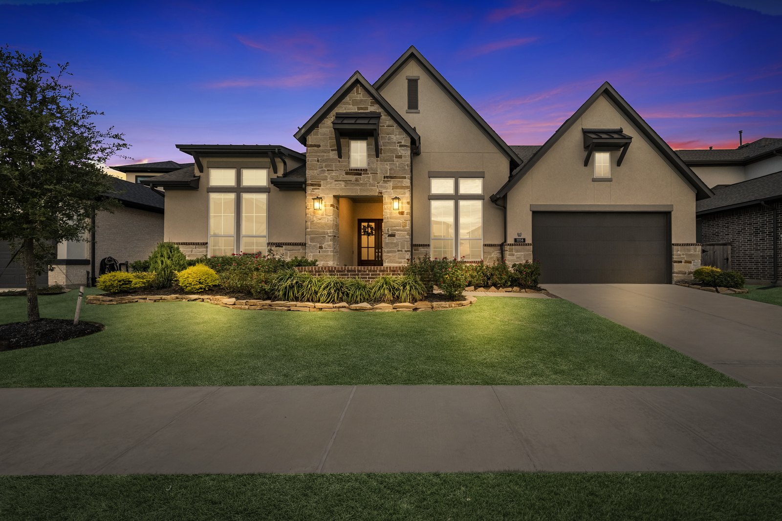 Virtual twilight of a two-story stone-front Houston-area home under a dramatic dusk sky
