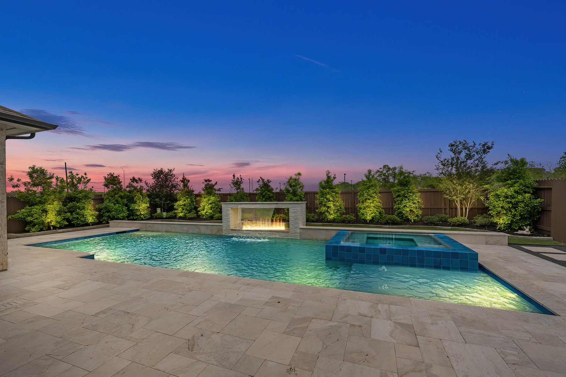 Virtual twilight of a backyard pool and spa with lit fire features at dusk